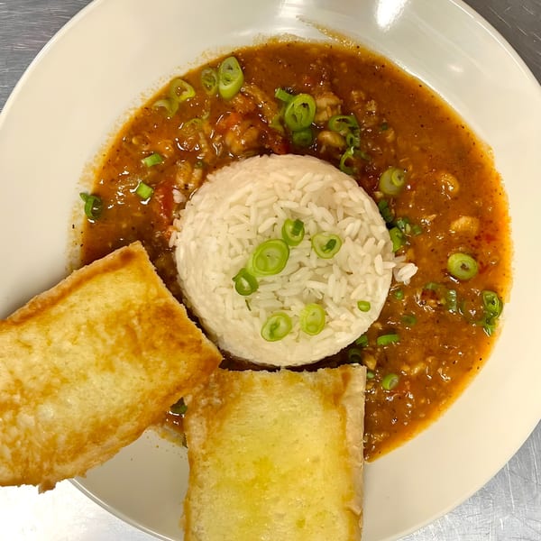 Krawfish Kai's seafood etouffee with rice, green onions, and two pieces of toasted bread.