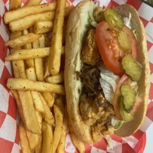 A Krawfish Kai seafood po'boy with fried shrimp, lettuce, tomato, and pickles, served with fries.