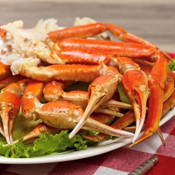 A platter of Krawfish Kai's steamed crab legs with lettuce on a red and white checkered tablecloth.