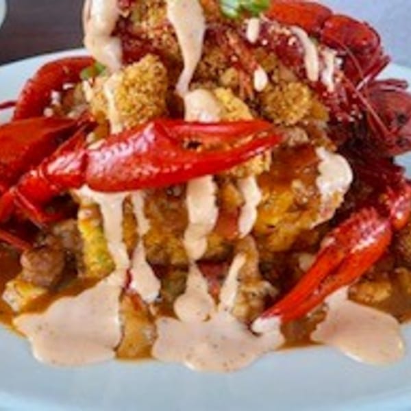 Krawfish Kai's seafood dish with crawfish, fried clusters, and creamy sauce on a light blue plate.