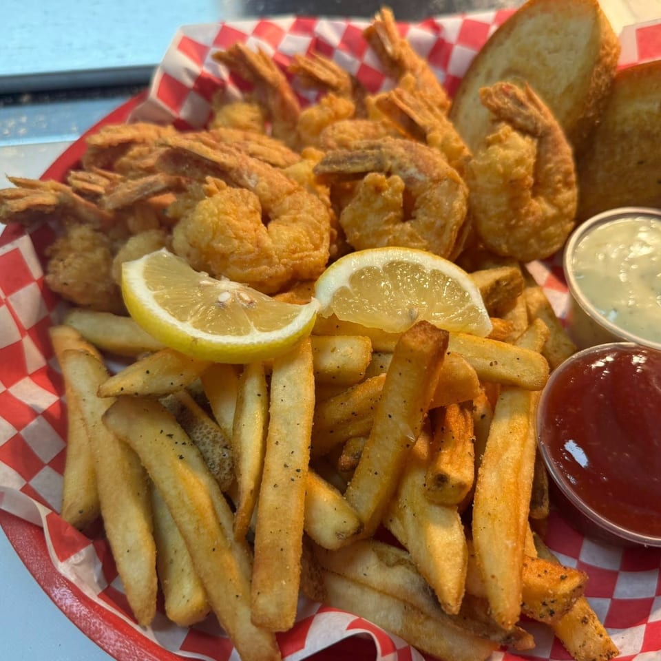 Krawfish Kai's fried shrimp and french fries with lemon wedges, garlic bread, ketchup, and tartar sauce.